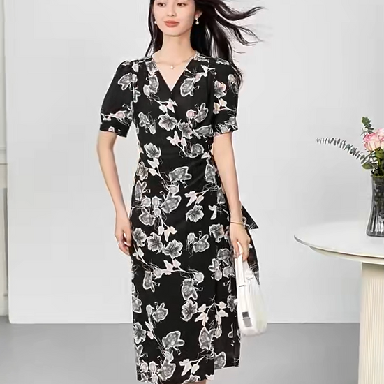 Video showcasing a woman's midi-length wrap silk dress in "Drifting Blossom" print, featuring a floral Guohua painting design on a textured black double crepe background with short gathered sleeves and a side-tie waist. — From Borcelleclothes.