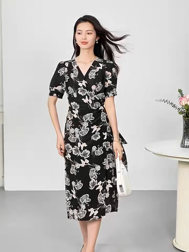 Video showcasing a woman's midi-length wrap silk dress in "Drifting Blossom" print, featuring a floral Guohua painting design on a textured black double crepe background with short gathered sleeves and a side-tie waist. — From Borcelleclothes.