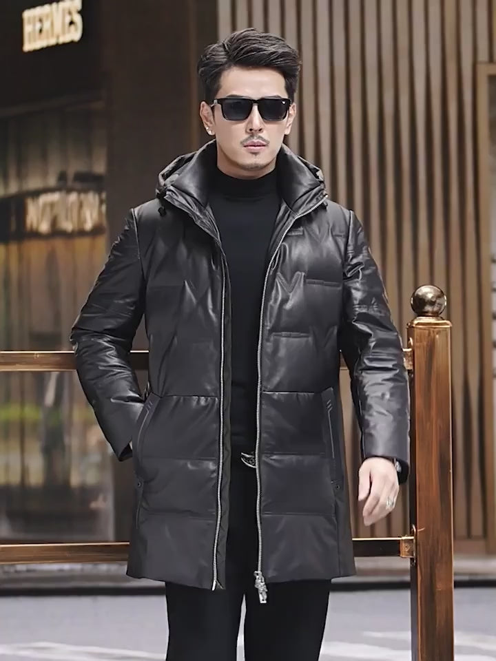 Video showcasing a Men’s down coat in embossed cowhide leather, Onyx color. Hood with drawcord and metal puller, geometric pocket details, structured silhouette — From Borcelleclothes.