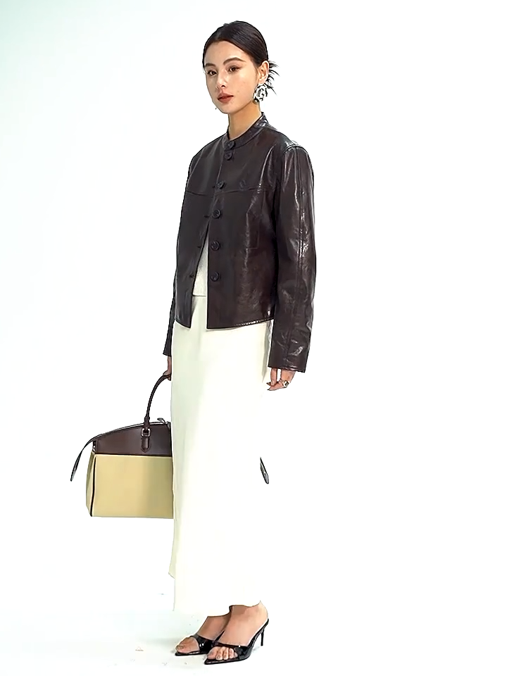 Video showcasing a Women's Full-grain oil-waxed goatskin overshirt jacket in First Impression. Architectural band collar, twin-needle detailing, and dynamic espresso pull-up undertones. — From Borcelleclothes.
