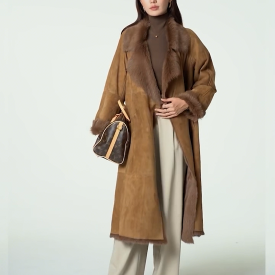 Video showcasing a Women's double-breasted goatskin coat with a fluid wrap design, notch lapels, and exposed fur edges. Available in Golden Mist color. — From Borcelleclothes.