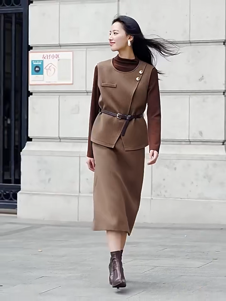 Video showcasing a tailored feminine set in Meet me in Istanbul color. Asymmetrical olive-brown wool blend vest, decorative molten gold buttons, slender leather belt, strict midi skirt with back vent. — From Borcelleclothes.