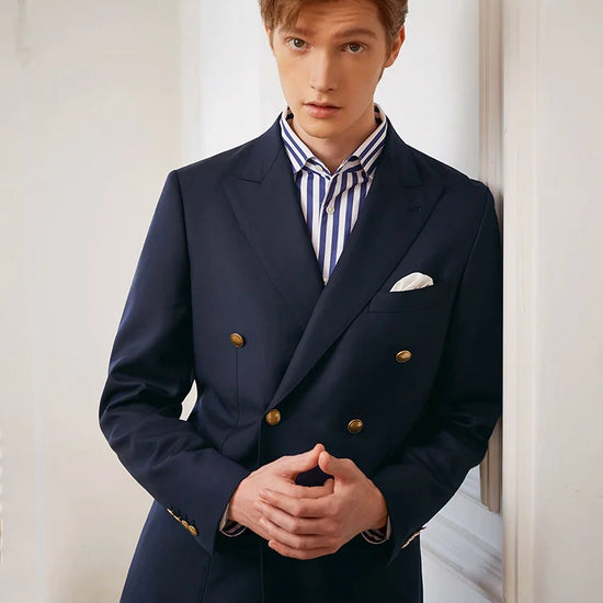 Video showcasing a Men's VBC Navy Blue Wool Suit with Brass Accents featuring a double-breasted blazer with peaked lapels, bold convex brass buttons, patch pockets, and slim-cut pants, crafted from 100% wool for a timeless and sophisticated look. — From Borcelleclothes.