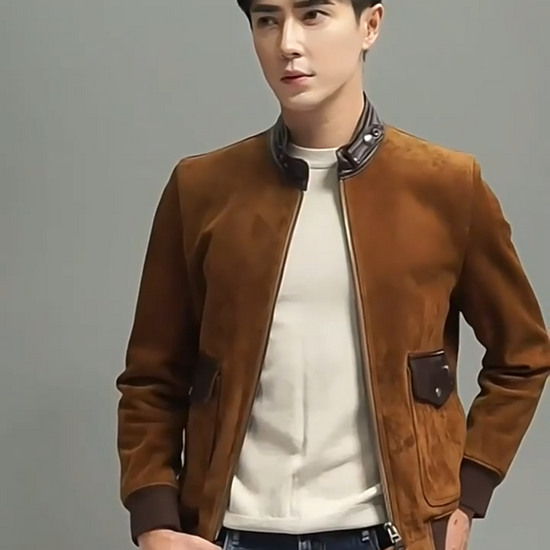 Video showcasing a Men's Nutmeg Suede Bomber — sheepskin suede, smooth-leather stand collar, curved flap pockets, rib cuffs and hem; tactile quiet luxury. From Borcelleclothes.