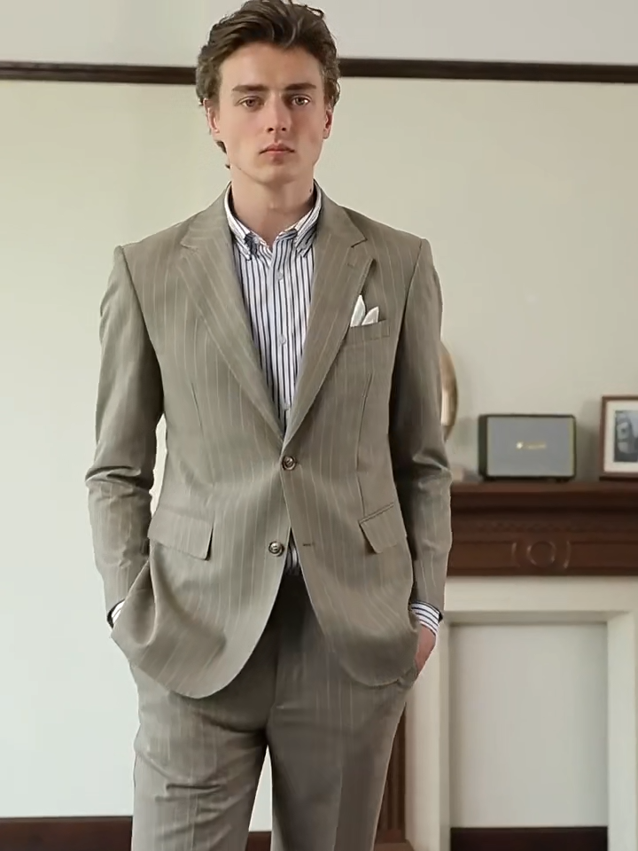 Video showcasing a Men’s grey olive pinstripe suit featuring a tailored blazer with notch lapels and horn buttons, straight-leg trousers with adjustable waistband, and optional matching vest. From Borcelleclothes.