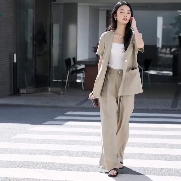 Video showcasing a Women's two-piece set in Olive Haze with crinkled texture, featuring a short-sleeved V-neck jacket and wide-leg trousers in a relaxed silhouette. From Borcelleclothes.