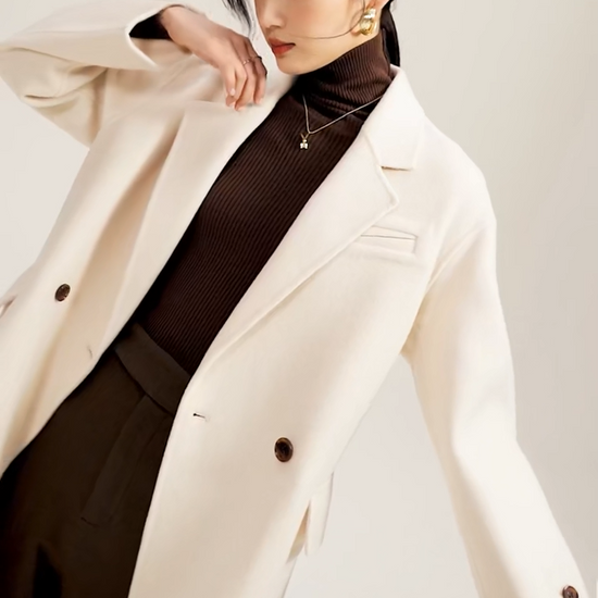Video showcasing a Women's double-sided wool coat in Piano color, featuring notch lapels, dropped shoulders, and a seamless, fluid silhouette. — From Borcelleclothes.