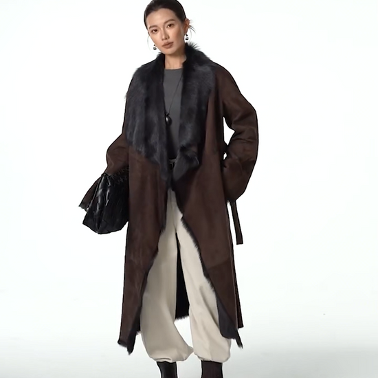 Video showcasing a Women's wide lapel double-faced goatskin coat in Raw Umber, with uncut edges and flowing fur, belted at the waist — From Borcelleclothes.