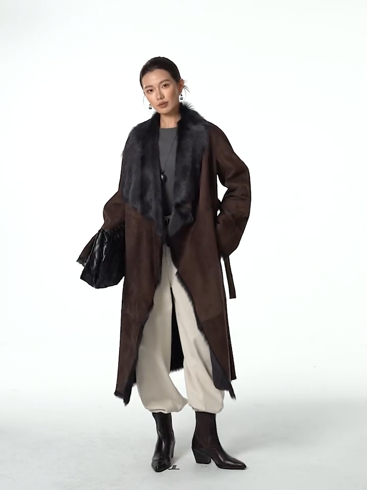 Video showcasing a Women's wide lapel double-faced goatskin coat in Raw Umber, with uncut edges and flowing fur, belted at the waist — From Borcelleclothes.