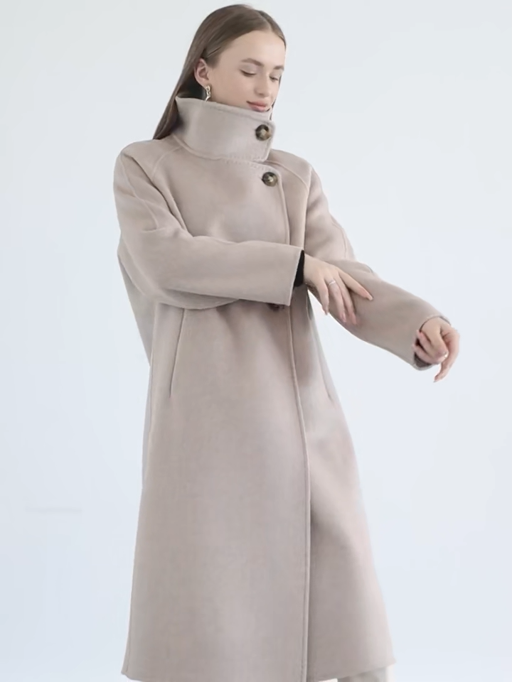 Video showcasing s Women's long, wrap-style double-sided wool coat in Sultana Spice, with an asymmetrical silhouette, saddle sleeves, and a high stand-up collar. — From Borcelleclothes.