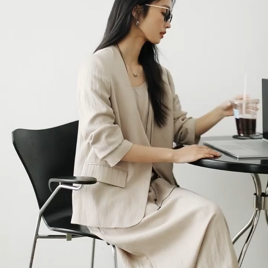 Video showcasing a Women’s two-piece set in Swiss Coffee color featuring a single-breasted jacket with long sleeves and an A-line camisole dress with adjustable straps. From Borcelleclothes.