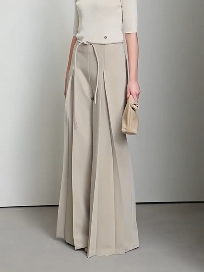 Video showcasing Women’s tailored draped trousers in Silk, featuring deep sculptural pleats and soft belt loops, styled with minimalist top and relaxed posture. From Borcelleclothes.