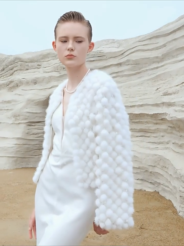 Video showcasing a Women’s mink mosaic coat made of individually attached sheared mink pom-poms and hand embroidery on mesh — in color White Whimsy. — From Borcelleclothes.