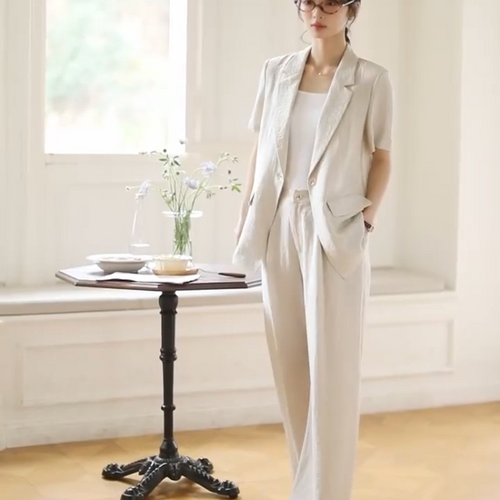 Video showcasing a Women's two-piece set in Wild Sand, featuring a short-sleeved blazer with notch lapels and crinkled wide-leg trousers, shown in natural light. From Borcelleclothes.