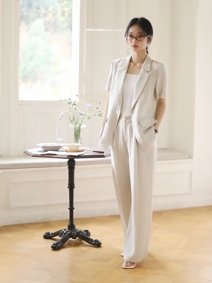 Video showcasing a Women's two-piece set in Wild Sand, featuring a short-sleeved blazer with notch lapels and crinkled wide-leg trousers, shown in natural light. From Borcelleclothes.