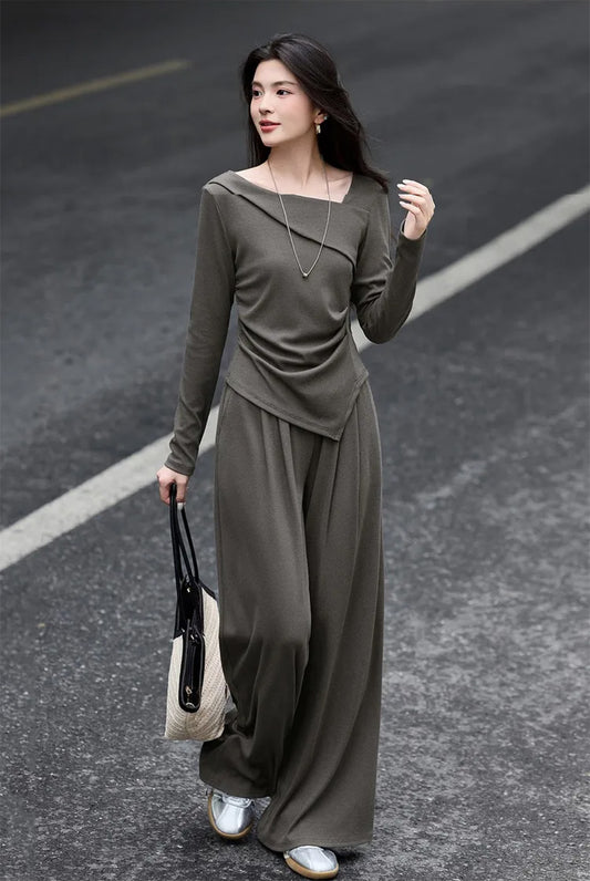 Woman wearing an asymmetrical ribbed knit set, holding a cream woven bag — From Borcelleclothes.
