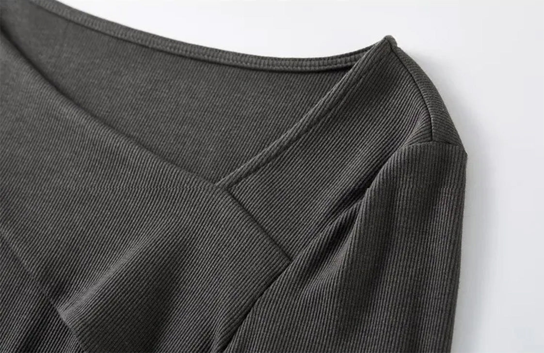 Close-up of the asymmetrical folded neckline on a woman’s ribbed knit top — From Borcelleclothes.