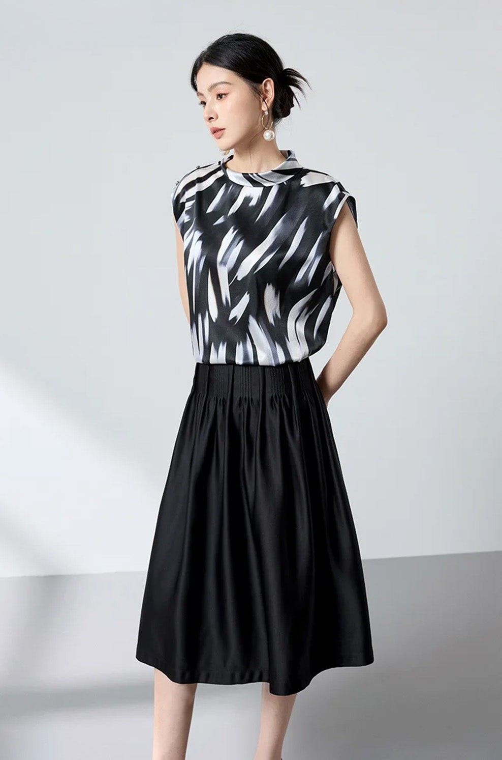 Model with hands behind back highlighting the clean drape of the silk satin blouse — From Borcelleclothes.