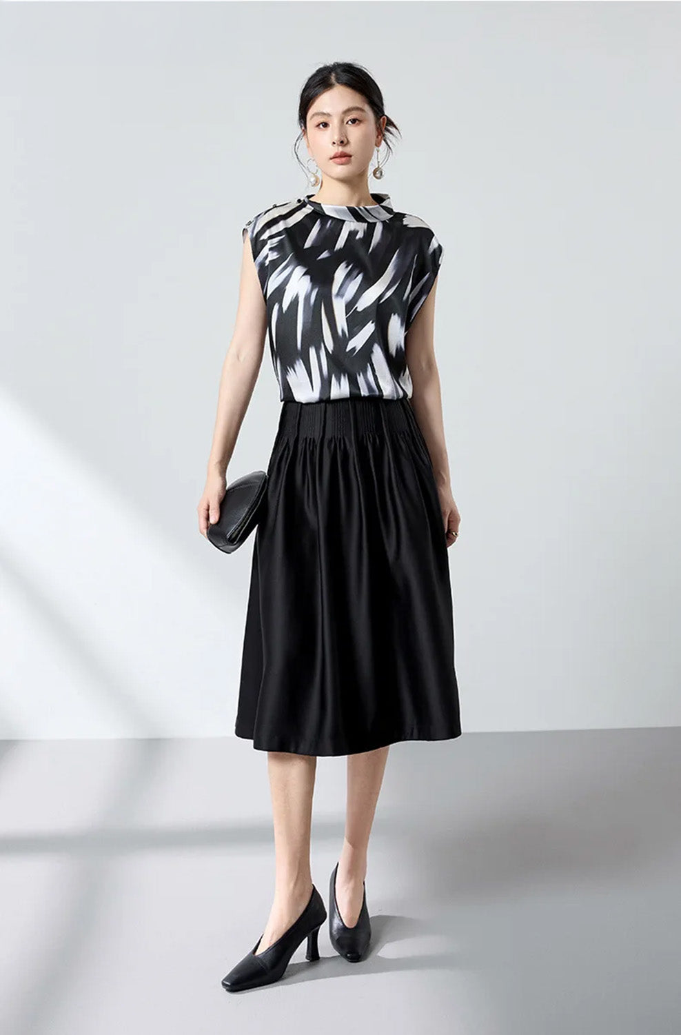 Standing model in Fleeting Impulse silk satin blouse holding a sleek clutch — From Borcelleclothes.