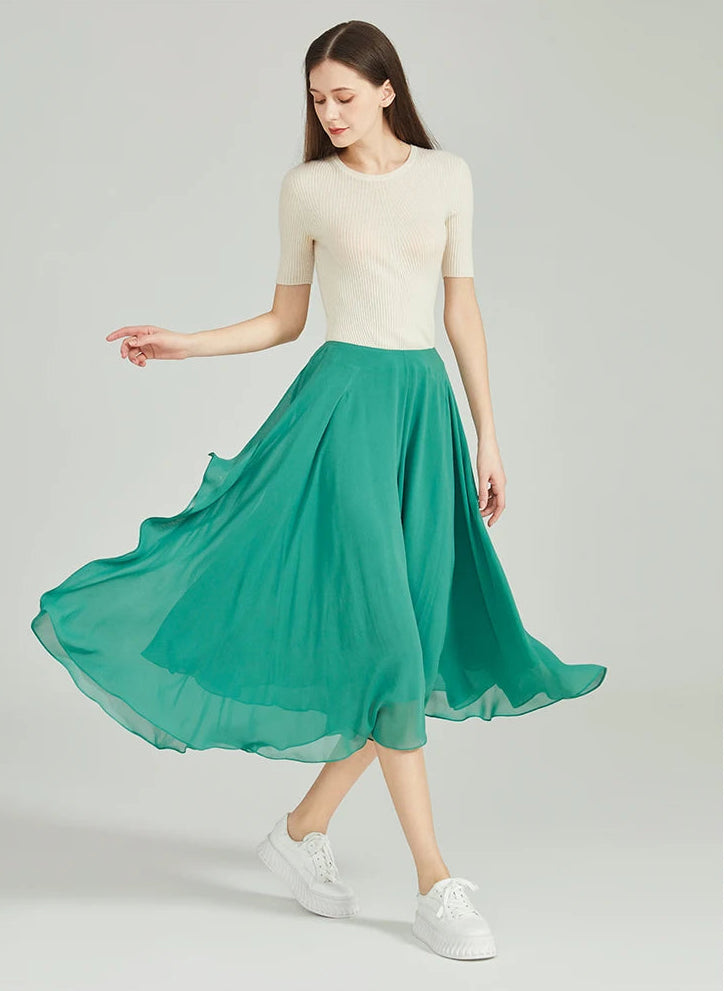 Side view of model walking in green Mulberry silk trousers with a swirling handkerchief hem — From Borcelleclothes.