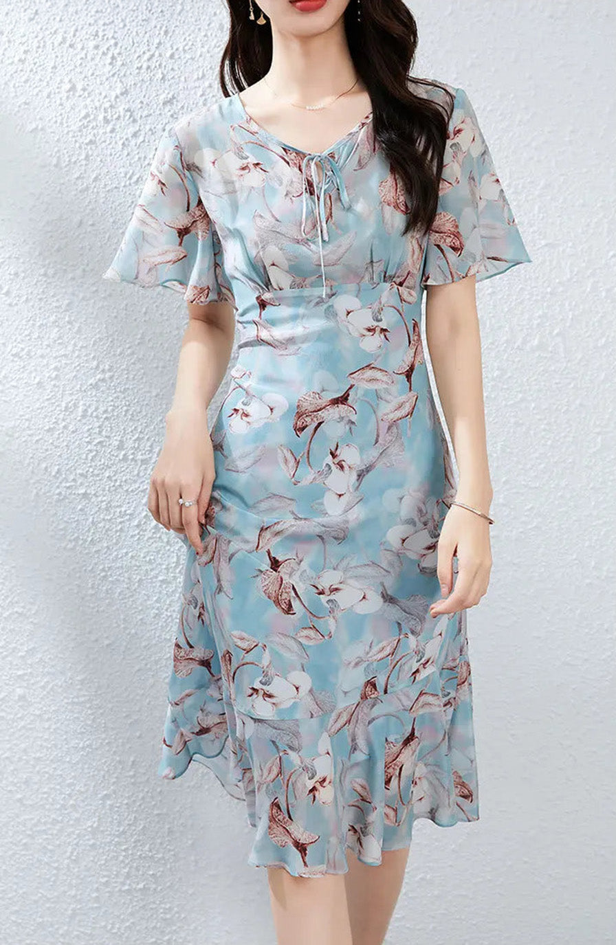 A woman gently lifting the skirt of her asymmetrical silk dress, capturing the weightless movement of the fabric — From Borcelleclothes.