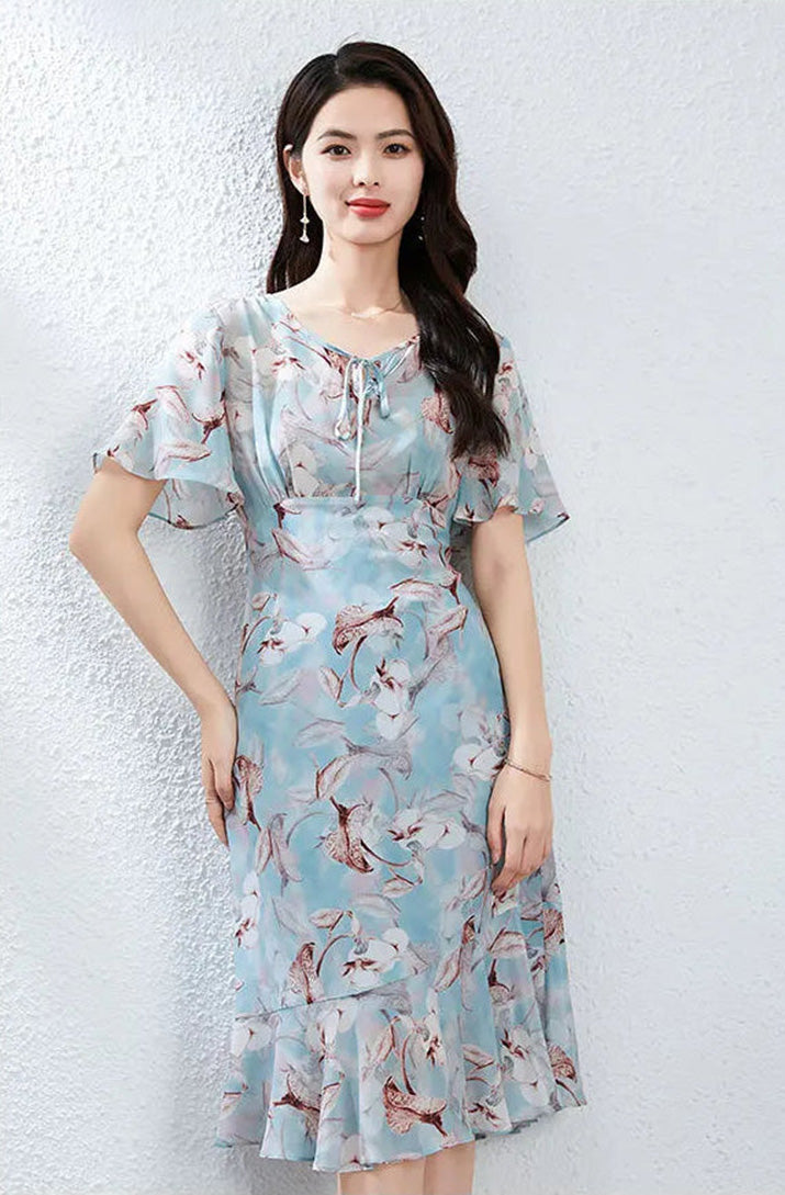 A woman in a Celestial Bauhinia silk dress resting her hand on her hip, demonstrating a powerful yet feminine posture — From Borcelleclothes.