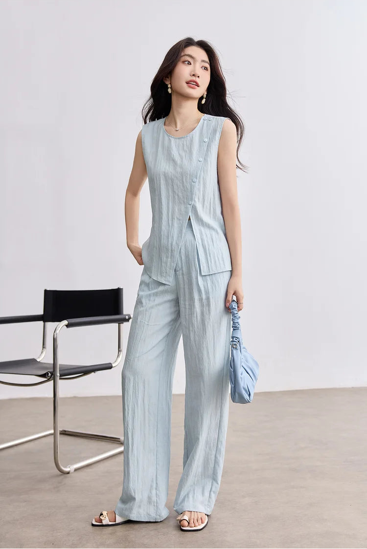 A woman holding a tonal blue bag that perfectly complements her asymmetrical Crinkled Freedom set — From Borcelleclothes.