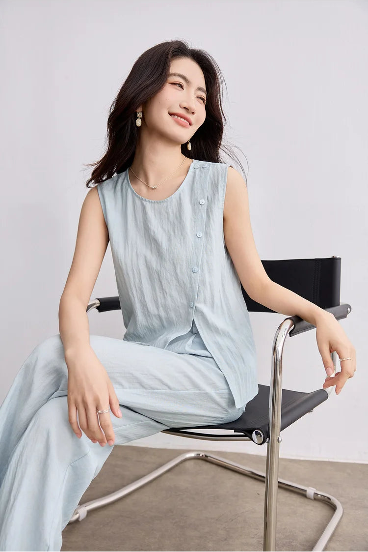A woman in a relaxed seated pose, looking to the side, wearing the blue Crinkled Freedom trousers set — From Borcelleclothes.