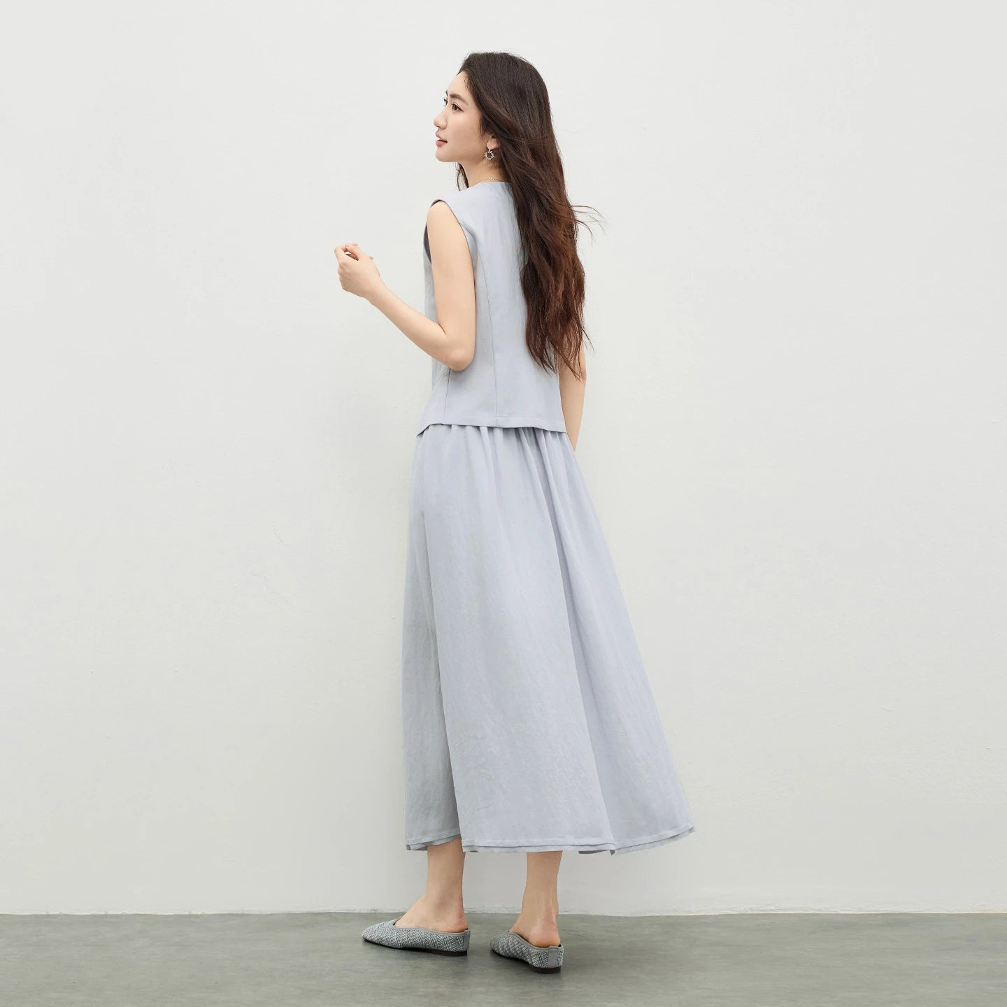 Back view of a woman wearing a lavender structured vest with princess seams and a midi skirt — From Borcelleclothes.