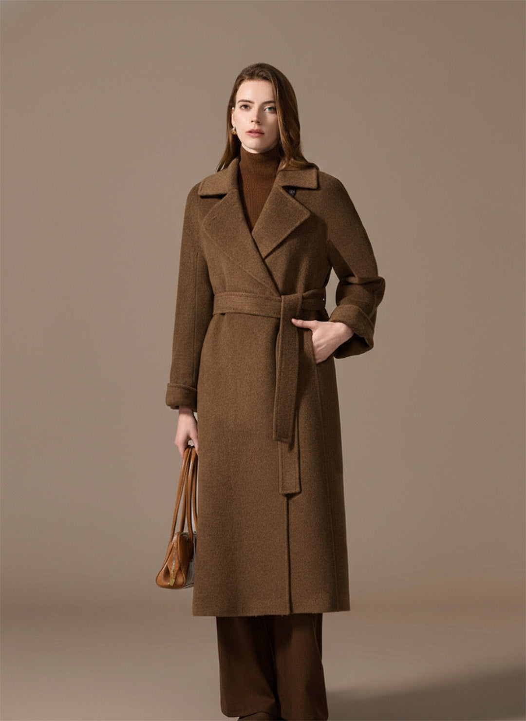 A woman’s hand tucked into the discreet princess seam pocket of the Gobi Haze grey coat. From Borcelleclothes.