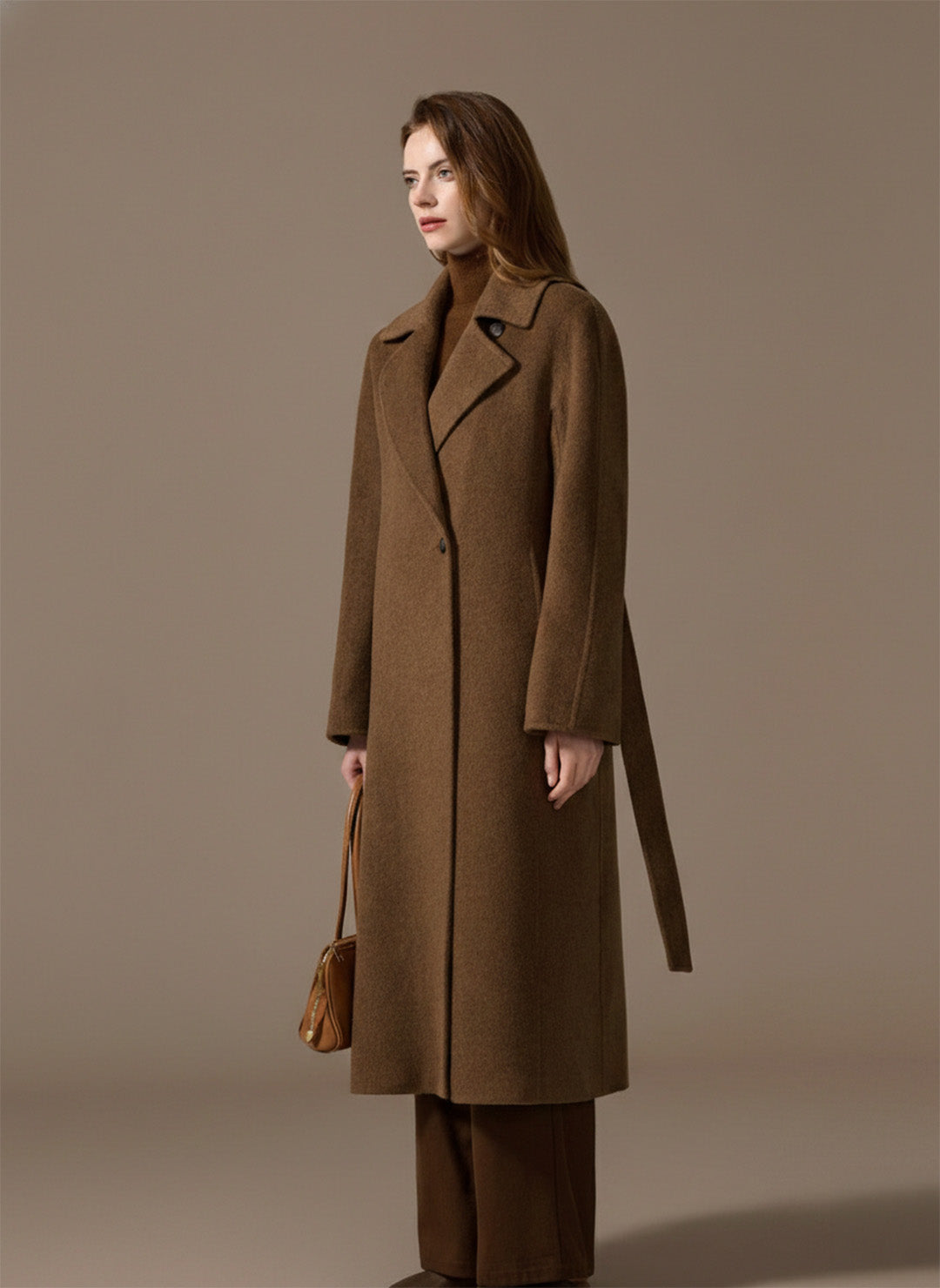 A serene portrait of a woman in the Gobi Haze Bactrian camel hair coat, looking ahead with quiet confidence. From Borcelleclothes.