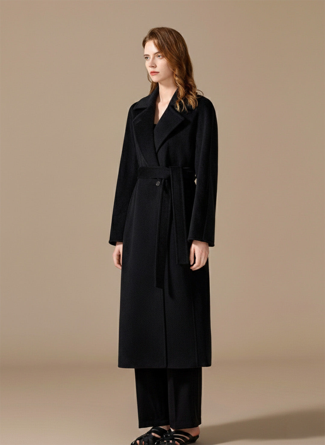 A woman turned slightly to the side, showing the sculpted fit and refined profile of the Nightfall black coat. From Borcelleclothes.