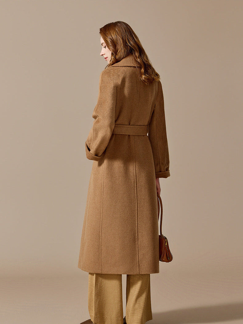 The elegant back silhouette of a woman wearing the long Tumbleweed camel hair coat, showcasing structural tailored seams. From Borcelleclothes.