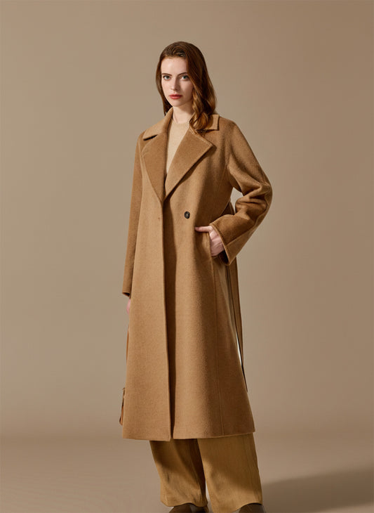 A woman rests her hand in the deep princess seam pocket of her Tumbleweed Bactrian camel hair coat. From Borcelleclothes.