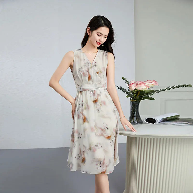 A woman looking down pensively while resting her fingertips on a table, capturing a moment of quiet inner freedom in her silk dress — From Borcelleclothes.