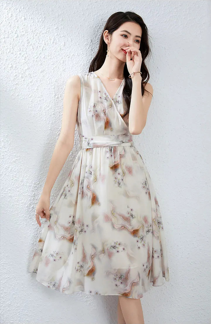A woman in a thoughtful pose, gently touching her lips with one hand while holding the soft hem of her watercolor silk skirt — From Borcelleclothes.