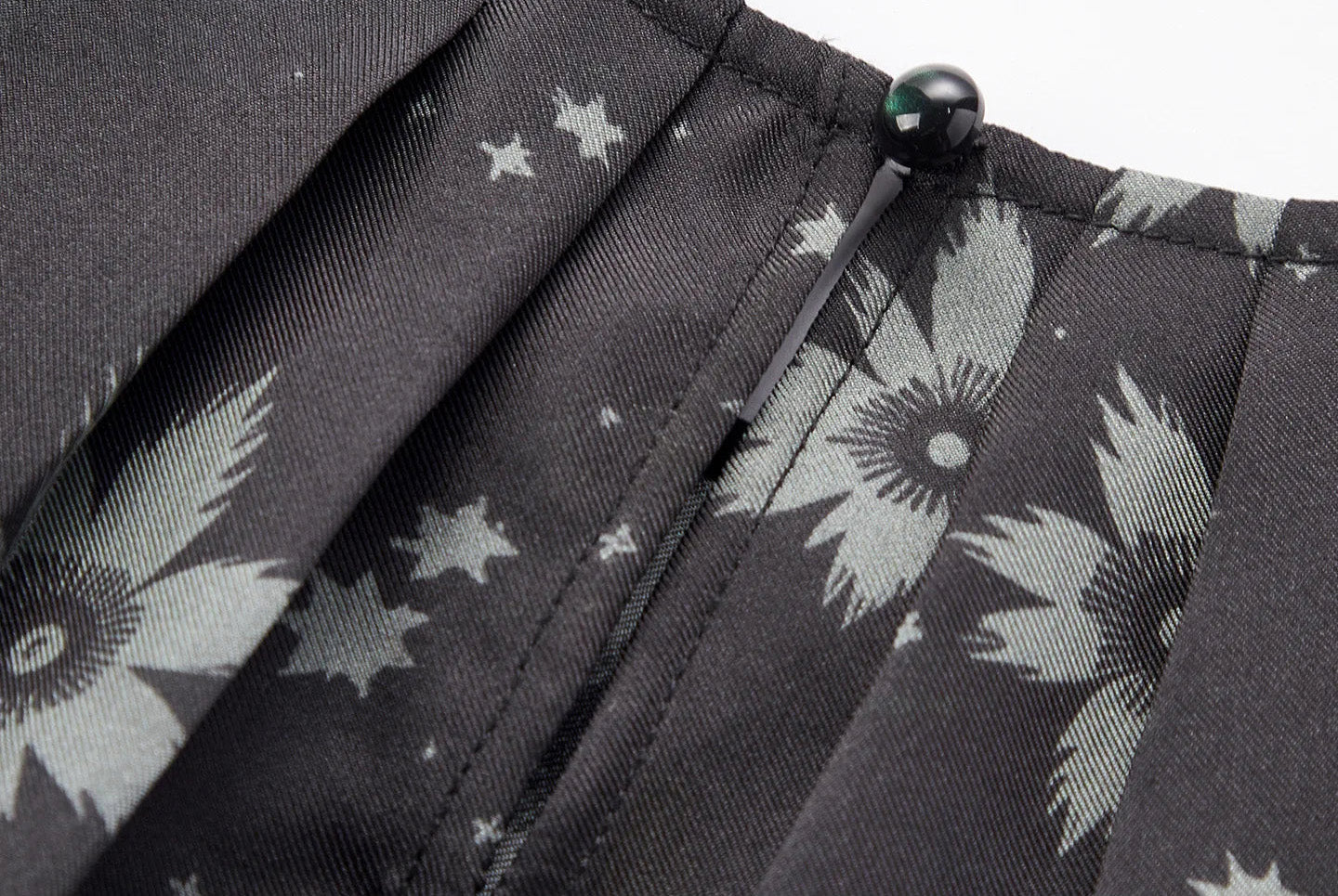 Close-up of the center-back slit and tonal dome shank button closure on a pleated silk blouse — From Borcelleclothes.