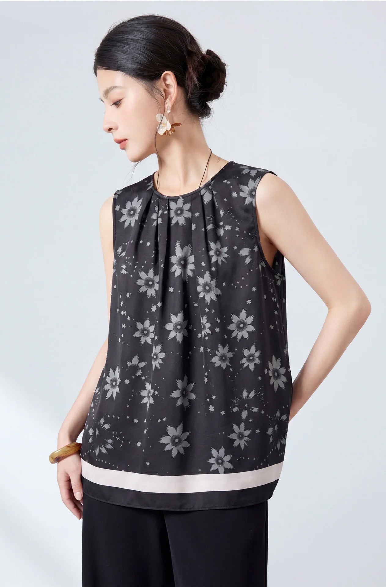 Model standing with hands on hips wearing a sleeveless silk twill blouse in Muted Sundrop border print — From Borcelleclothes.