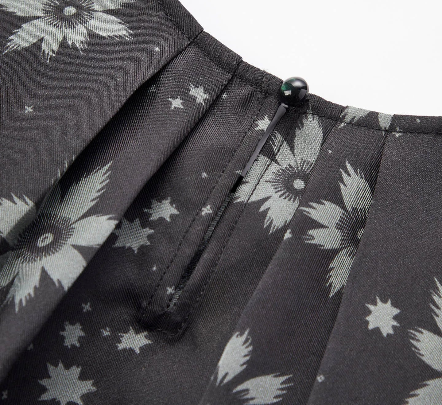 Close-up of the back neckline showing symmetrical inward-facing pleats and loop button fastening — From Borcelleclothes.