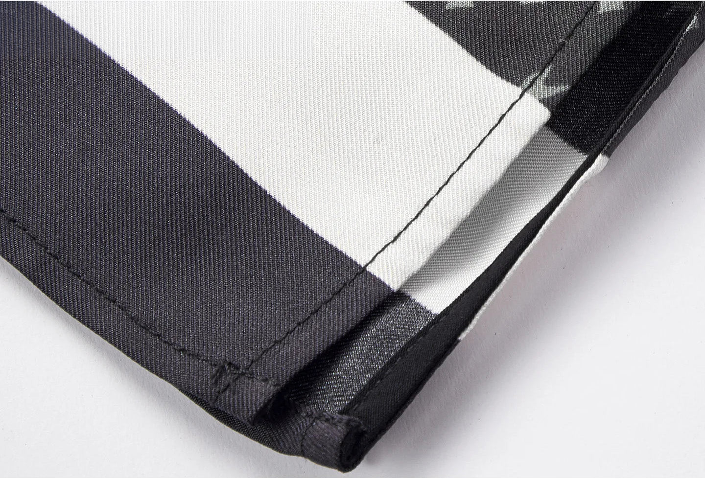 Detail shot of the straight hem side slit and contrast ivory border stripe on a silk twill top — From Borcelleclothes.
