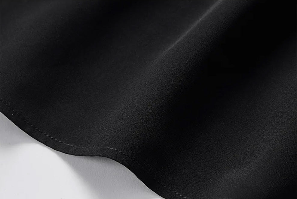 Detailed view of the bottom hem tucked into pleated white trousers, showing the fluid hang and clean edge finishing — From Borcelleclothes.