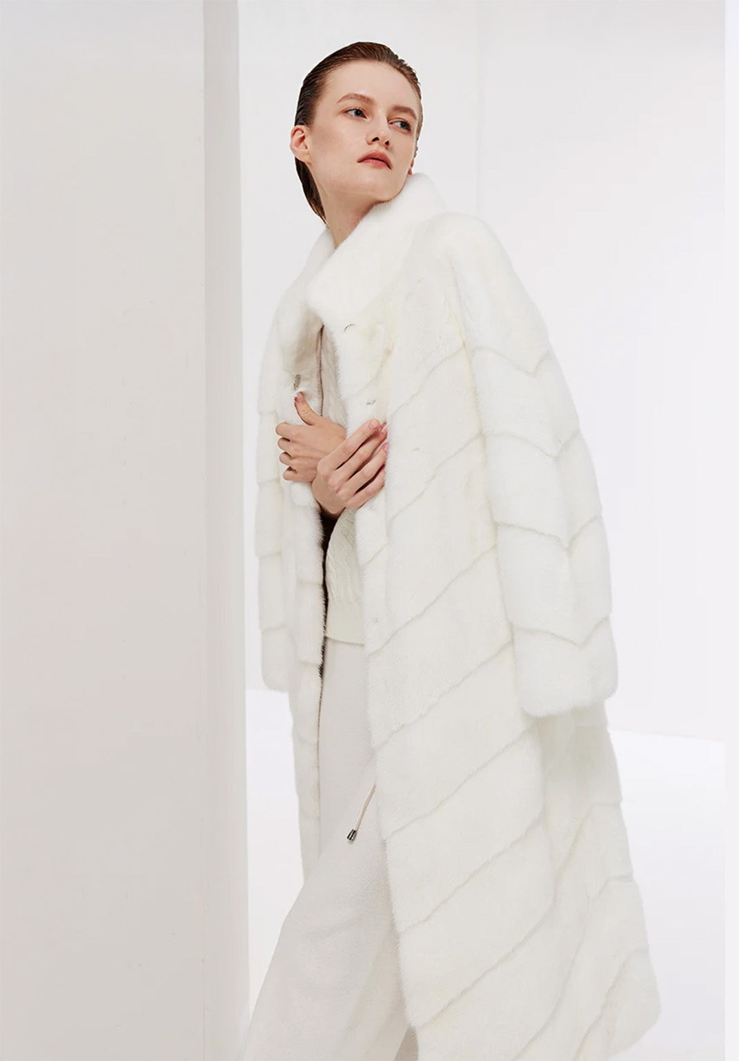 Women’s chevron sheared mink coat in Calm, model holding both front edges with crossed hands — From Borcelleclothes.