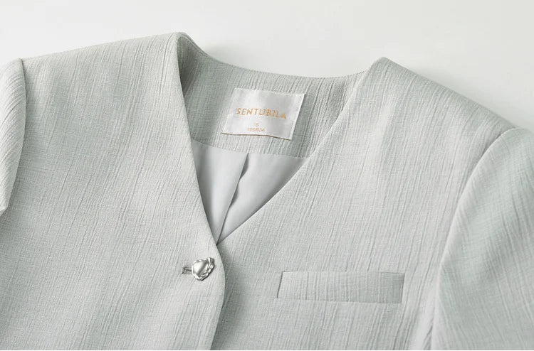 Close-up of the clean collarless V-neckline on the sage-grey cropped jacket. From Borcelleclothes.