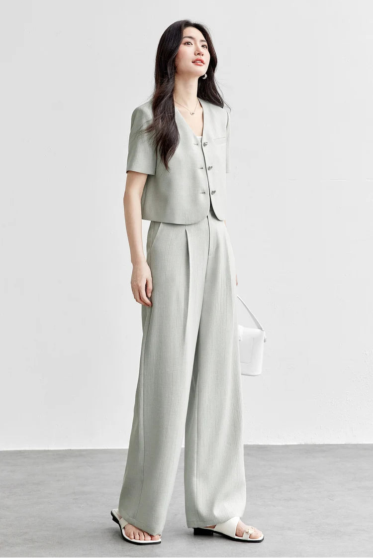 A woman wearing the Named by Frost viscose set, looking up to highlight the structured V-neckline and the airy, architectural fit of the suit. From Borcelleclothes.