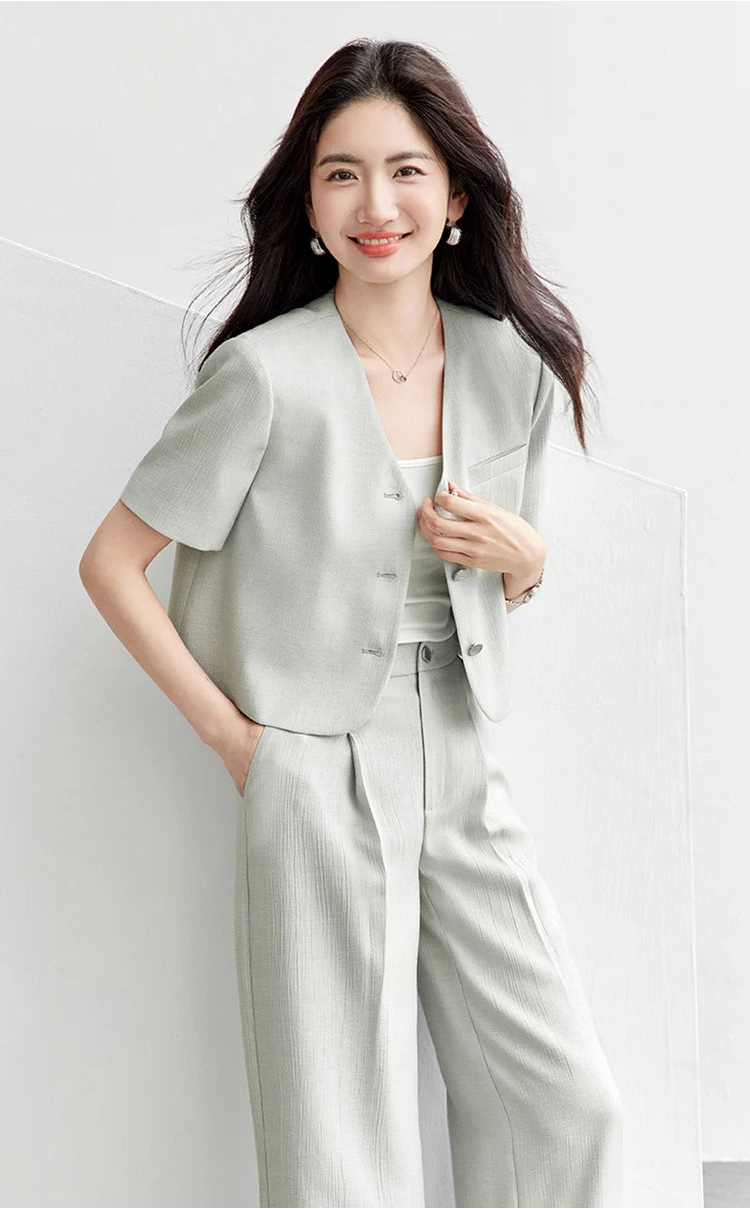 A woman in an unfastened Named by Frost jacket, touching the front edge to reveal the soft drape of the crinkled viscose fabric. From Borcelleclothes.