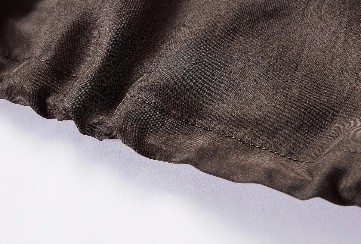 Detail view of adjustable drawstring bottom hem on Bitter Chocolate silk blouson — From Borcelleclothes.