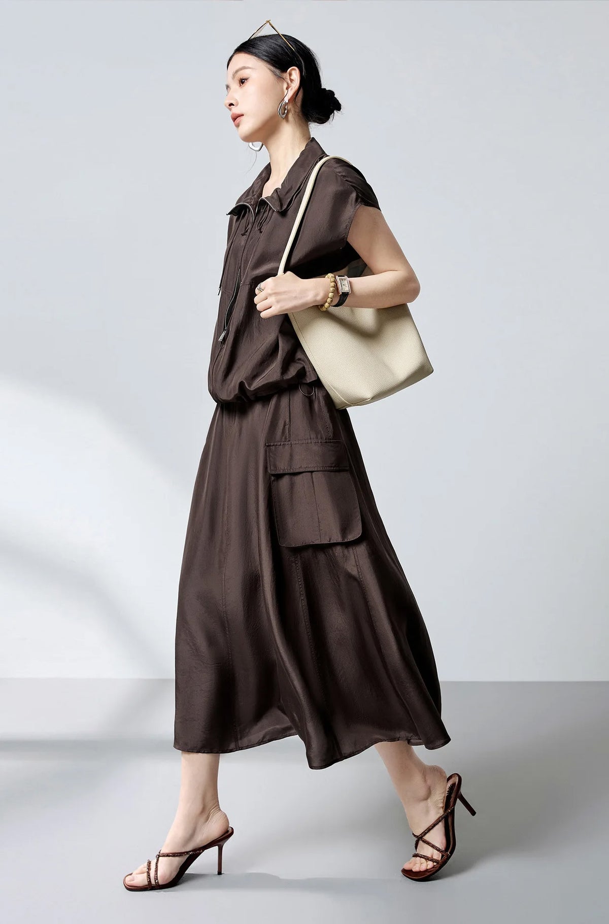 Side view of model walking in silk blouson with shoulder bag — From Borcelleclothes.