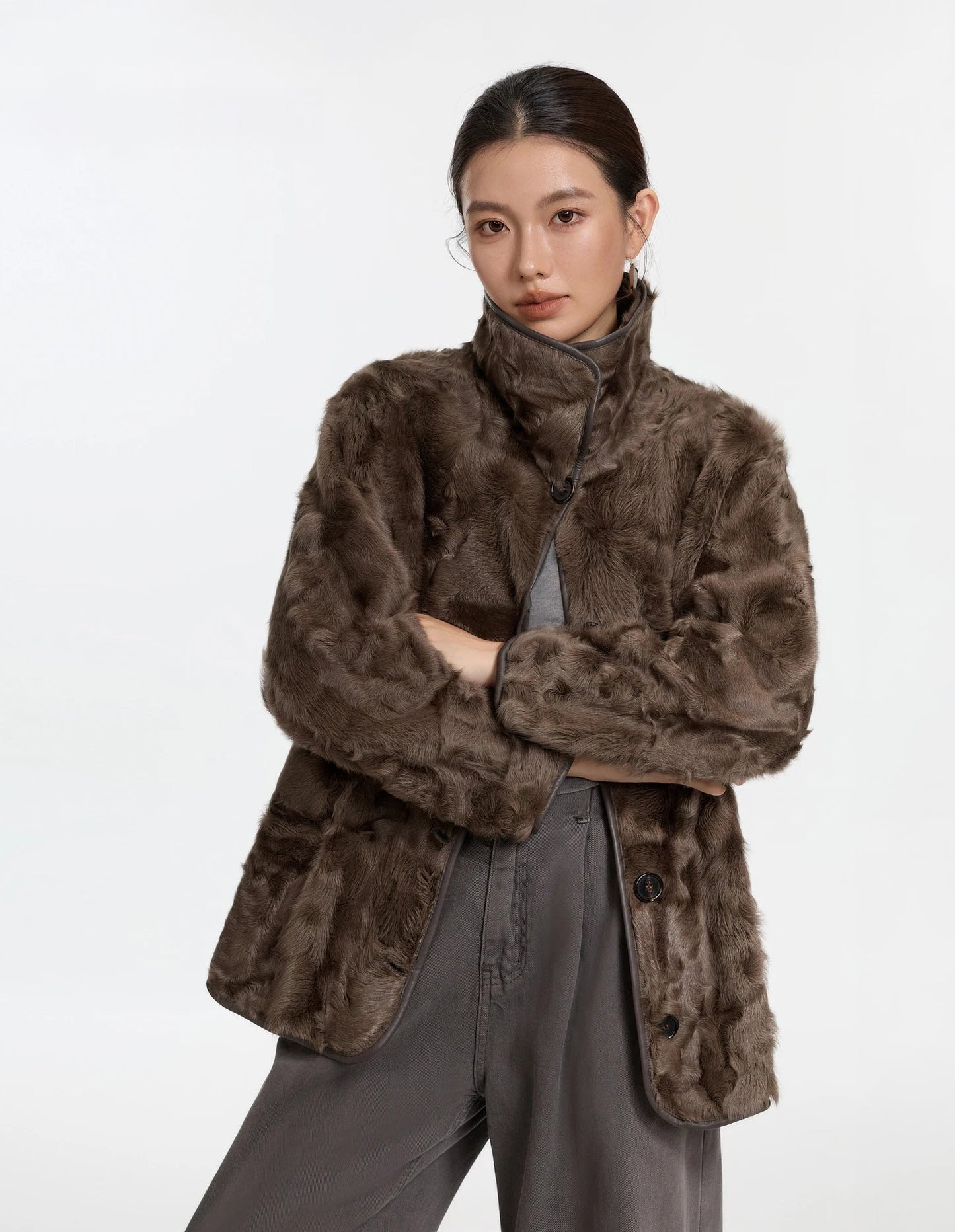 Model with arms crossed in the Clove Ripples coat, fur side worn outward, expressing quiet warmth and comfort — From Borcelleclothes.