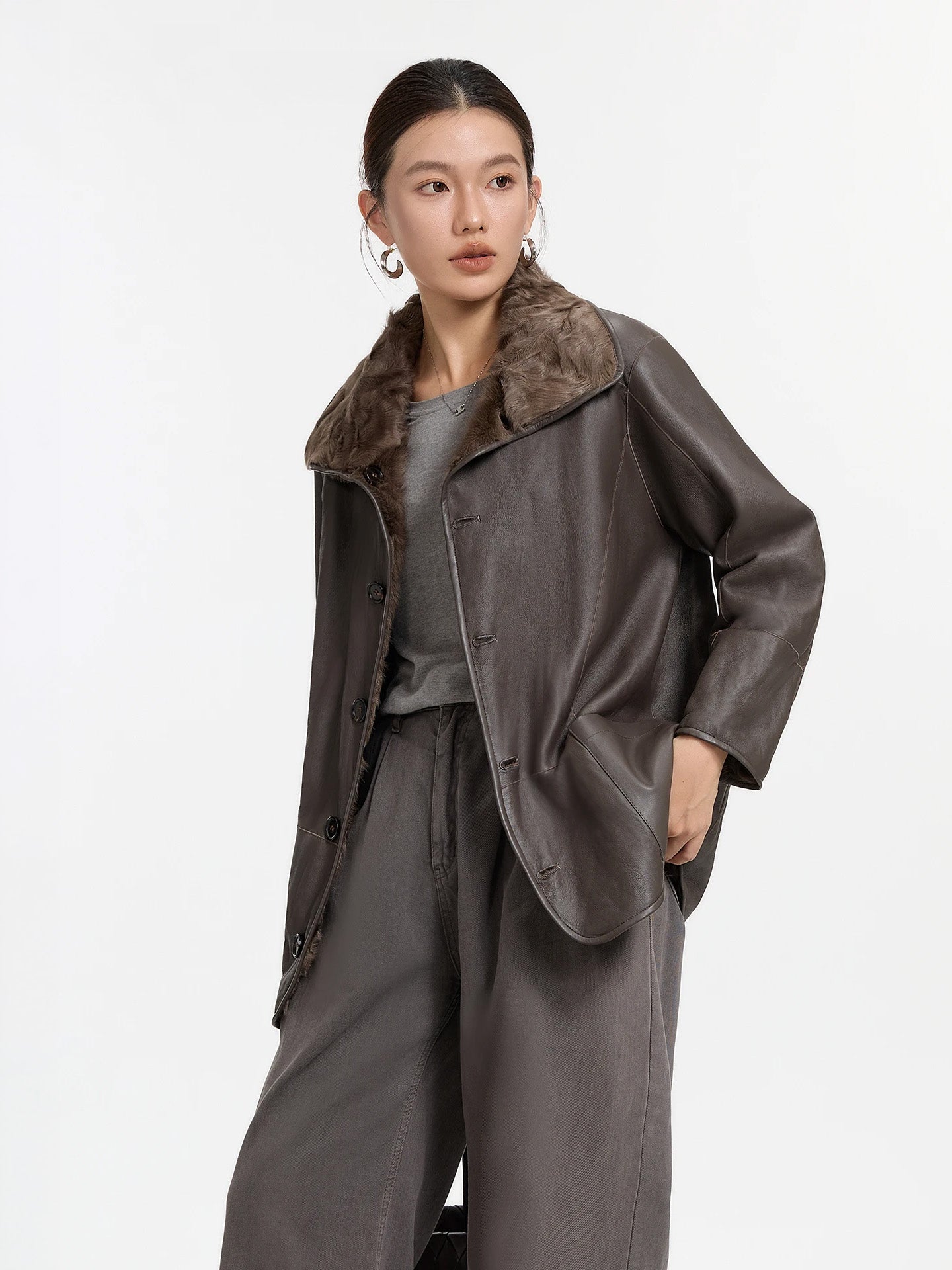 Model lifting the hem of the Clove Ripples coat worn leather side out, revealing the double-faced construction — From Borcelleclothes.