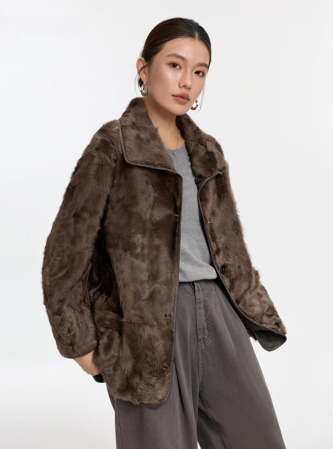Model gently touching the hem of the Clove Ripples shearling coat, fur side out, with the soft texture visible — From Borcelleclothes.